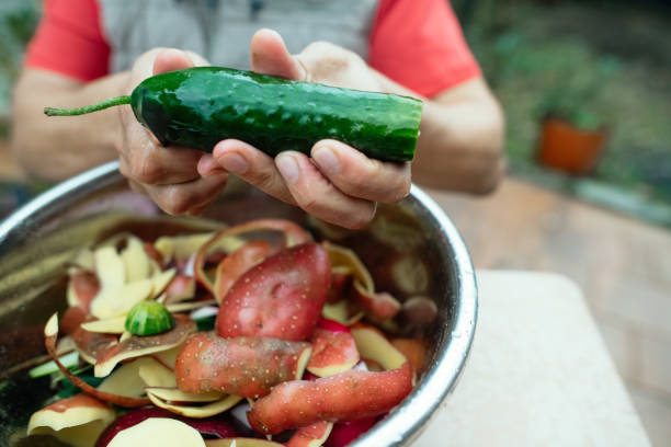 close up of a man peeling vegetables and making compost from leftovers at an open kitchen outdoors at back yard. sustainable lifestyle and zero waste cooking concept. - carrot close up copy space counter top ストックフォトと画像