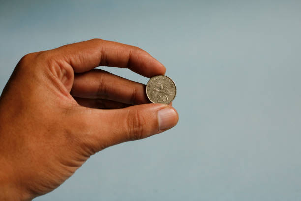istock Close up hand holding twenty cent dollar coin singapore 1941946565