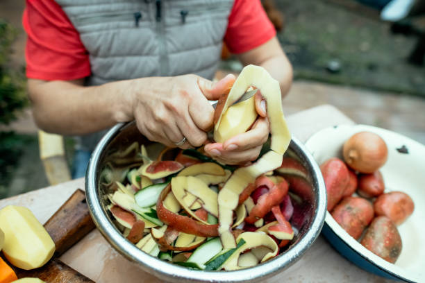 Close up of a man peeling vegetables and making compost from leftovers. Sustainable lifestyle and zero waste cooking concept.