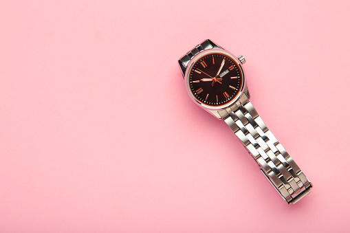 Wrist watch on pink background. Women watch. Top view