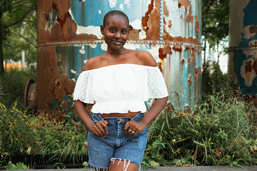 Black woman with shaved short hair posing in Williamsburg, New York.