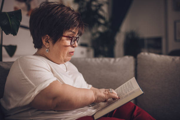 istock Serene Woman Reading Book on Couch at Home 1942004369
