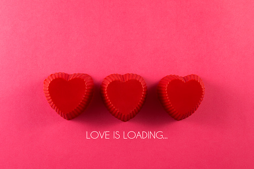 Loading process with heart shaped muffin cups for Valentine’s Day concept on a pink background