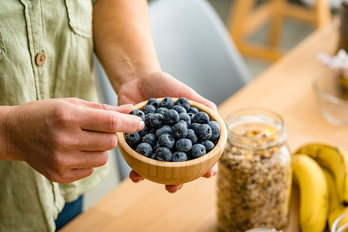 Woman eating organic blueberries from a bowl. High resolution 42Mp studio digital capture taken with Sony A7rII and Sony FE 90mm f2.8 macro G OSS lens