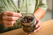 Close up of woman's hands taking organic raisins from glass jar