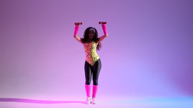 Positive 80s Girl with Dumbbells doing Aerobics Exercise over purple background