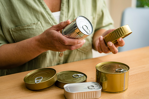 Woman reading expiration date of canned food. High resolution 42Mp studio digital capture taken with Sony A7rII and Sony FE 90mm f2.8 macro G OSS lens