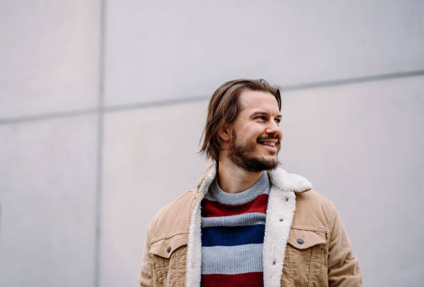 istock Smiling male model looking at the distance while posing over the blank wall 1942066705