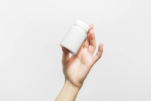 istock hand holding a white plastic jar with pills 1942069923