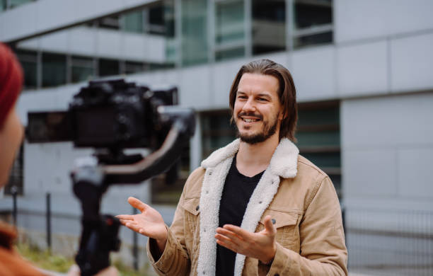 istock Long haired actor man talking gesturing while cameraman shooting him in urban street 1942073147