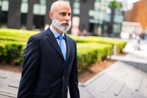 Smiling bald businessman walking in a city