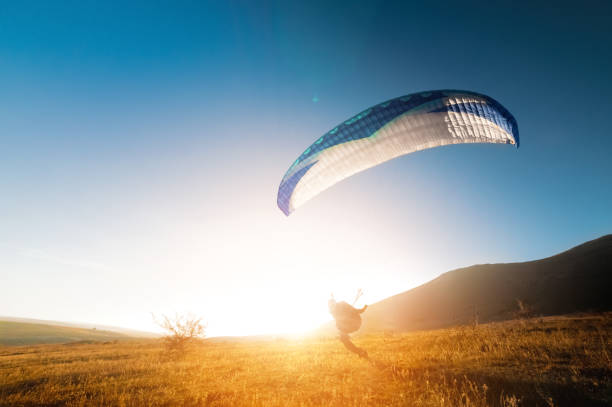 istock Launching a speedwing from a mountain. A paraglider is preparing to take off from a mountain, running along the yellow autumn grass against the sun 1942138236