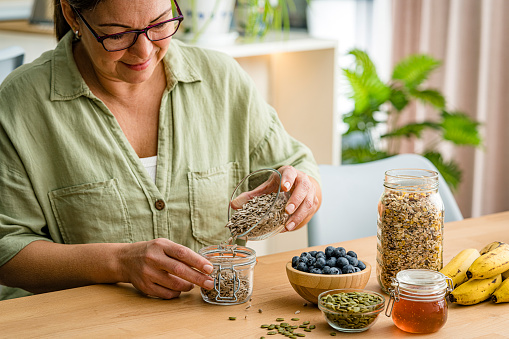Close up of woman filling airtight jar with sunflower seeds. High resolution 42Mp studio digital capture taken with Sony A7rII and Sony FE 90mm f2.8 macro G OSS lens