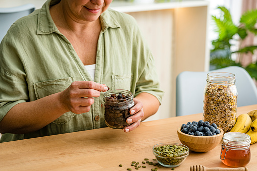 Woman eating organic raisins from glass jar High resolution 42Mp studio digital capture taken with Sony A7rII and Sony FE 90mm f2.8 macro G OSS lens