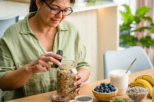 Woman preparing healthy vegan and nutritious breakfast. Oatmeal , honey, berries, seeds, fruits. High resolution 42Mp studio digital capture taken with Sony A7rII and Sony FE 90mm f2.8 macro G OSS lens