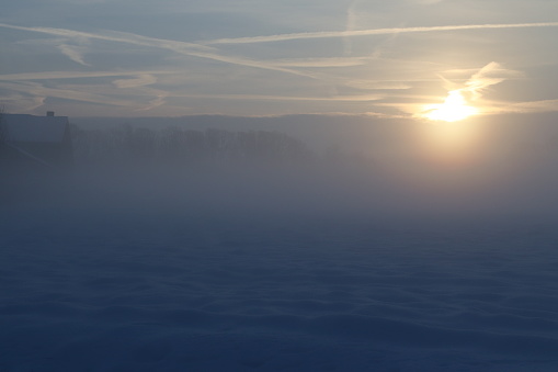 A calming sunrise at a field full of snow in the morning when it was misty.