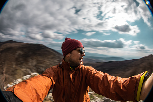 Male hiker taking a selfie high on mountain on cold autumn day.