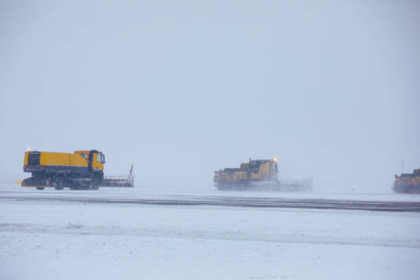 Closed airport during heavy snowfall. Snow plows removing snow from closed runway. Contept of extreme weather in transportation with copy space.