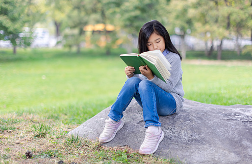 Reading Little Girl with Sitting on Stone