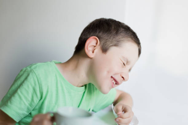 Emotional baby in shirt and blue jumper on white background.
