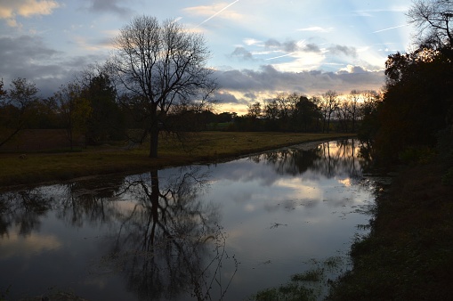 Sunset over the Conestoga River, in Eastern Lancaster County, Pennsylvania.  The river has mirrored reflections of the clouds and trees.