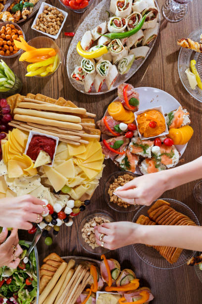 istock High angle view of dinner table with food and human hands 1942305796