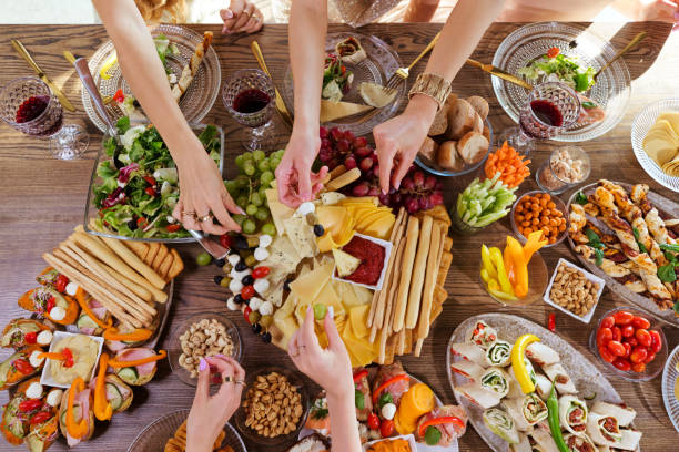istock High angle view of dinner table with food and human hands 1942305818