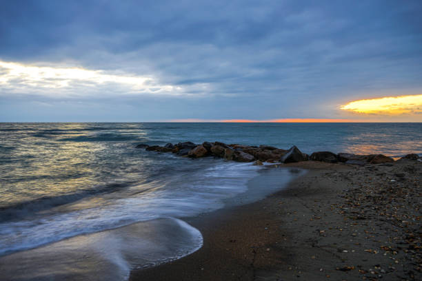 istock Waves crashing on a beach at sunset 1942315284