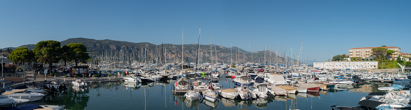 Nice, France – June 13, 2023: A cluster of boats moored in a serene harbor, framed by majestic mountains