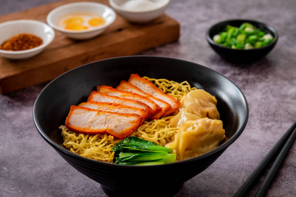 istock Egg noodle with red roasted pork and wonton in black bowl 1942325314