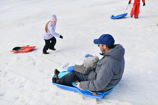 The father with child sledding in the snow