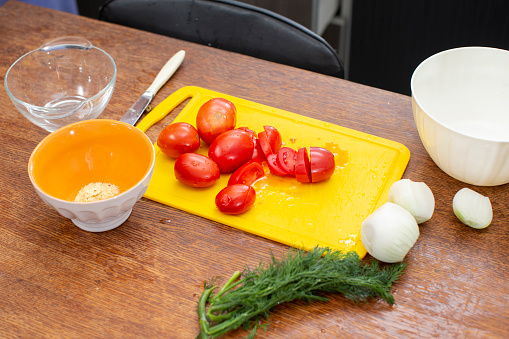 There is a cutting board with tomatoes and onions on the table. Prepare vegetable salad.