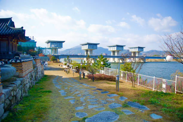 Sangju City, South Korea - November 17th, 2023: A wide shot of Nakdan Weir and the Nakdong River, featuring a cobblestone path leading to a temple in front of the Seated Maae Bodhisattva, blending natural and cultural landscapes.
