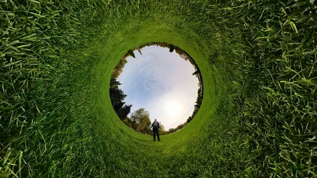 Man standing in center of inverted grass field.