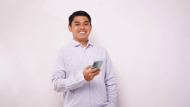 istock Asian man holding mobile phone showing enthusiastic expression against gray background 1942390277