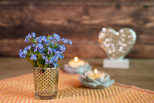 Forget-me-not Bouquet with candle on wooden table