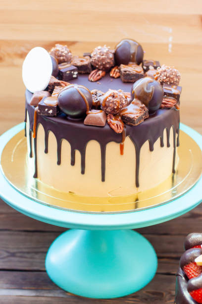 istock Chocolate cake decorated with truffles, sweets, cookies, pecan nuts with melted chocolate and salted caramel on the top 1942403256