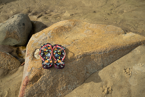 Flip-flops on the rocks at the beach, summer, beach, and sun concept.