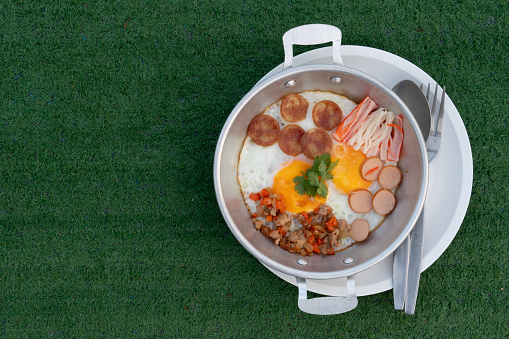 Pan Fried Eggs Topped with minced pork, hot flowers, Chinese sausage and crab sticks. Served in a galvanized plate and placed on a plate.  Placed on artificial grass