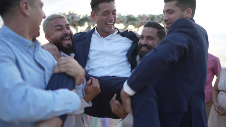 Groom having fun with friends in the wedding party on the beach