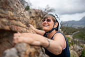 Smiling senior woman having fun during rock climbing adventure