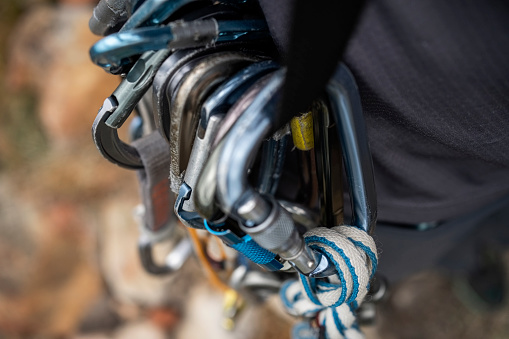 Via ferrata set with colorful carabiner hook hangs on a wire rope on a rocky mountain.