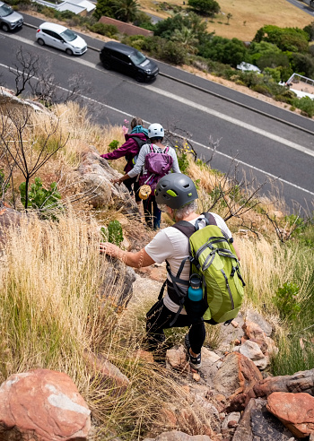 High angle view of a group of senior women with helmets and backpacks walking back to their cars after a hike