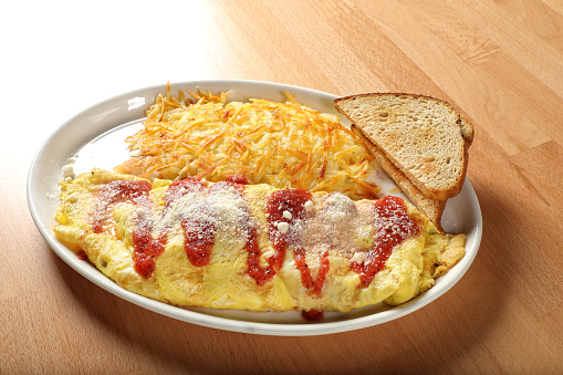 Scrambled eggs, omelette, close up. Breakfast with a pan-fried eggs, cup of tea, tomatoes on old wooden table