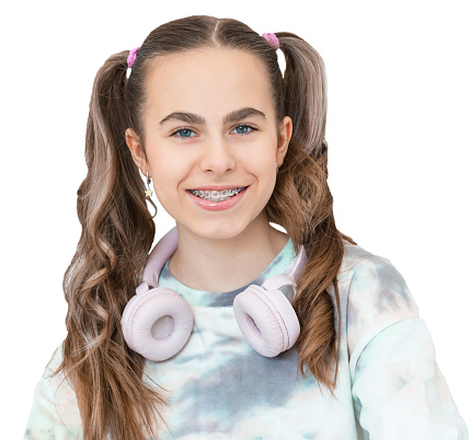 Portrait of smiling beautiful teenage girl with braces listening music in headphones, audiobook, lecture. Smiling girl with braces in everyday life.