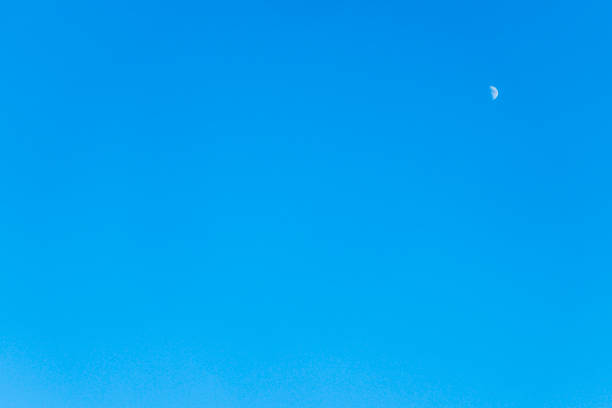 clear afternoon sky with a small crescent moon