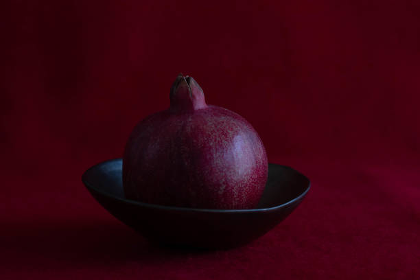 Pomegranate in a copper ceramic bowl on Red Background