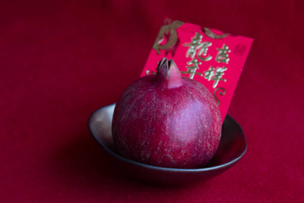 Pomegranate in a copper ceramic bowl and Red Lucky Envelope for Good Luck  on Red Background