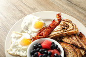 Two eggs with fruits breakfast dish on wooden table