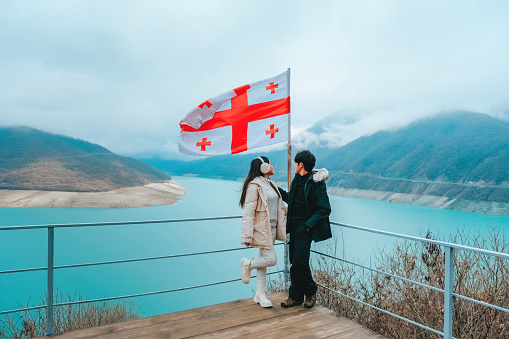 Couple tours Zhinvali reservoir, tourist attraction with mountain views and blue river in Georgia.